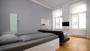 Une chambre à coucher moderne avec un lit, une table de chevet, un miroir et un téléviseur.