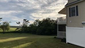 A two-story house with a covered porch and a large lawn. - Lovely house with gorgeous marsh views! (Wells)