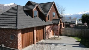 A two-story house with a sloped roof, a brick exterior, and a wooden fence.