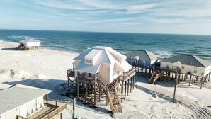 A beachfront property with elevated wooden structures, a sandy beach, and the ocean in the background. - Private dipping Pool, a Game Room, roof-top Crow's Nest - Kowabunga (Dauphin Island)