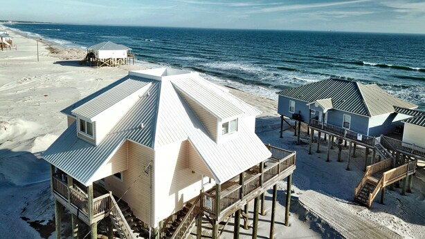 A beachfront property with multiple buildings, including a main house with a large balcony and a smaller structure nearby. - Private dipping Pool, a Game Room, roof-top Crow's Nest - Kowabunga (Dauphin Island)