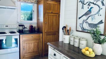 A kitchen with wooden cabinets, a stove, a coffee maker, and a painting of birds.