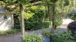 A garden with gravel paths, potted plants, and a wooden pergola.