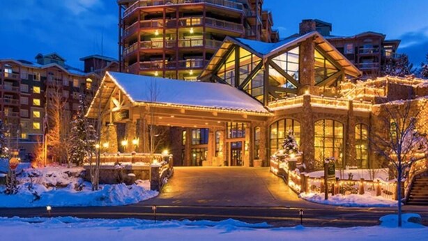 Um hotel de vários andares com entrada imponente, grandes janelas e arredores cobertos de neve.