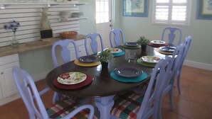 Un comedor con una mesa redonda, sillas y un estante con adornos.