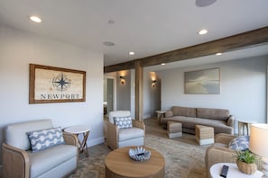 A modern living room with a sofa, armchairs, a coffee table, and a wall-mounted compass sign.