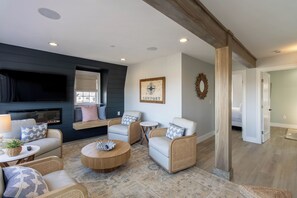 Un salon chaleureux avec une cheminée, des sièges confortables et un téléviseur fixé au mur.