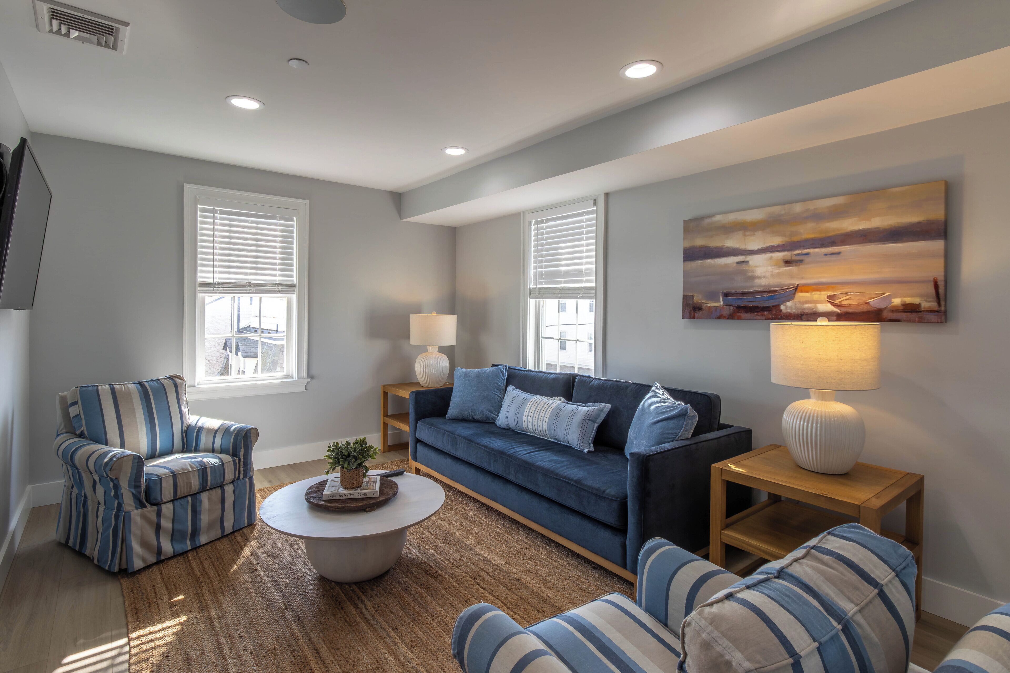 A living room with a sofa, armchairs, a coffee table, and a painting on the wall.