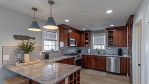 A modern kitchen with wooden cabinets, granite countertops, and stainless steel appliances.