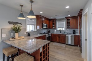 Una cocina moderna con armarios de madera, encimeras de granito y electrodomésticos de acero inoxidable.