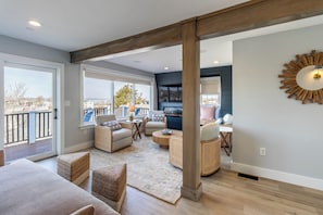 A spacious living area with a balcony, wicker furniture, and a large wall-mounted mirror.