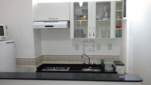 A kitchen with white cabinets, a microwave, a stove, and a sink. - Studio in Copacabana close to the beach and next to the Metro, flexible check in. (Rio de Janeiro)