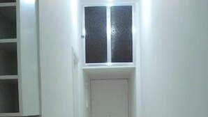 A narrow hallway with a wooden floor, a white door at the end, and a small window above it. - Studio in Copacabana close to the beach and next to the Metro, flexible check in. (Rio de Janeiro)