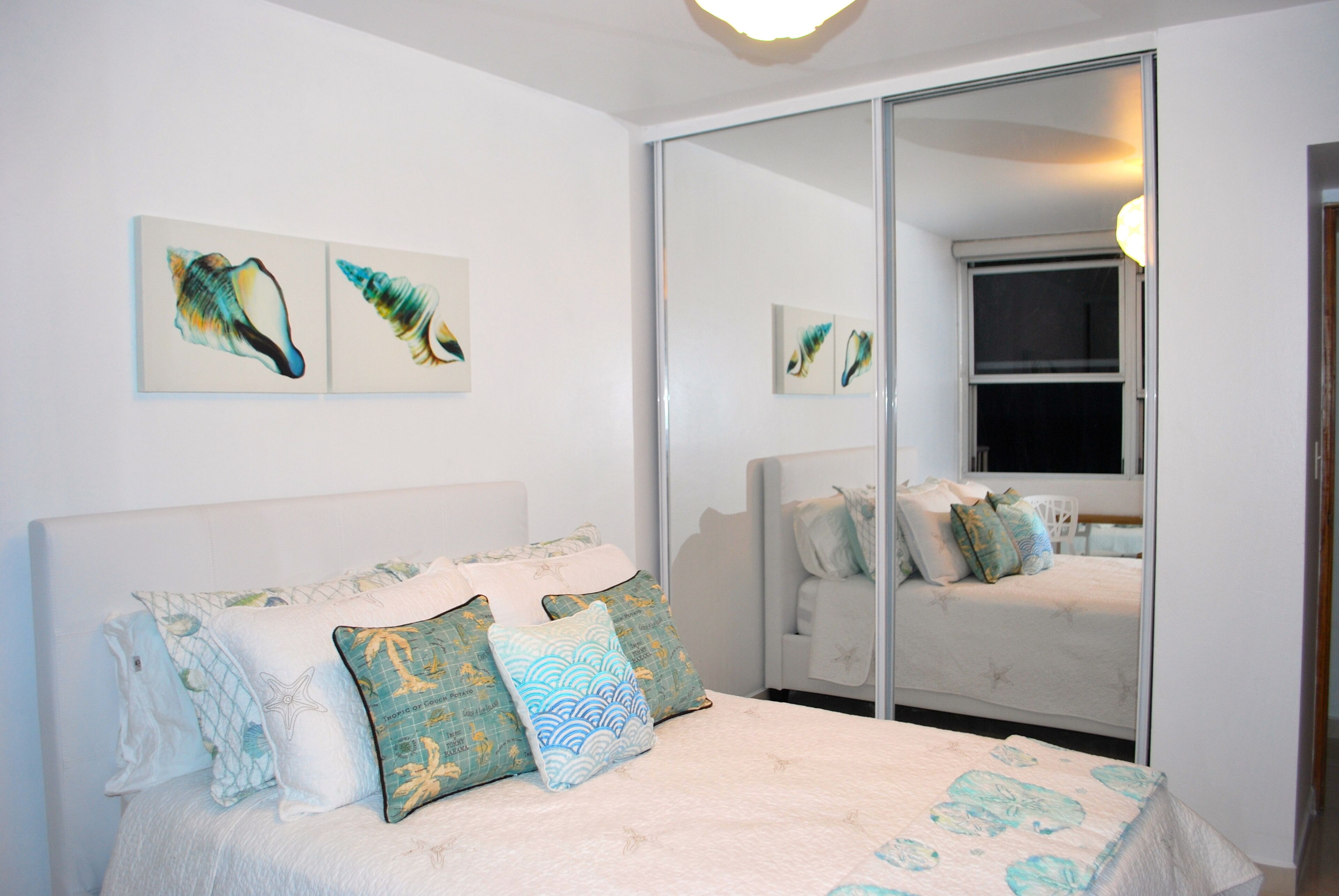 A bedroom with a bed, pillows, and wall art.