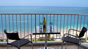 A balcony with a table and two chairs overlooking a beach. - Stunning 18th floor remodeled 2/2, beachfront! MONTHLY RENTALS CONSIDERED (Carolina)