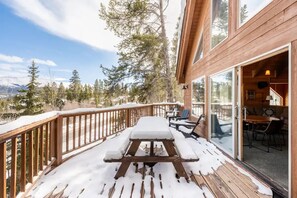 Enjoy meals on the deck overlooking the mountainous landscape with evergreen trees.