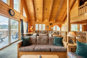 Relax in this cabin-style accommodation with a comfortable sofa, dining table for two, and large windows offering views of the surrounding landscape.