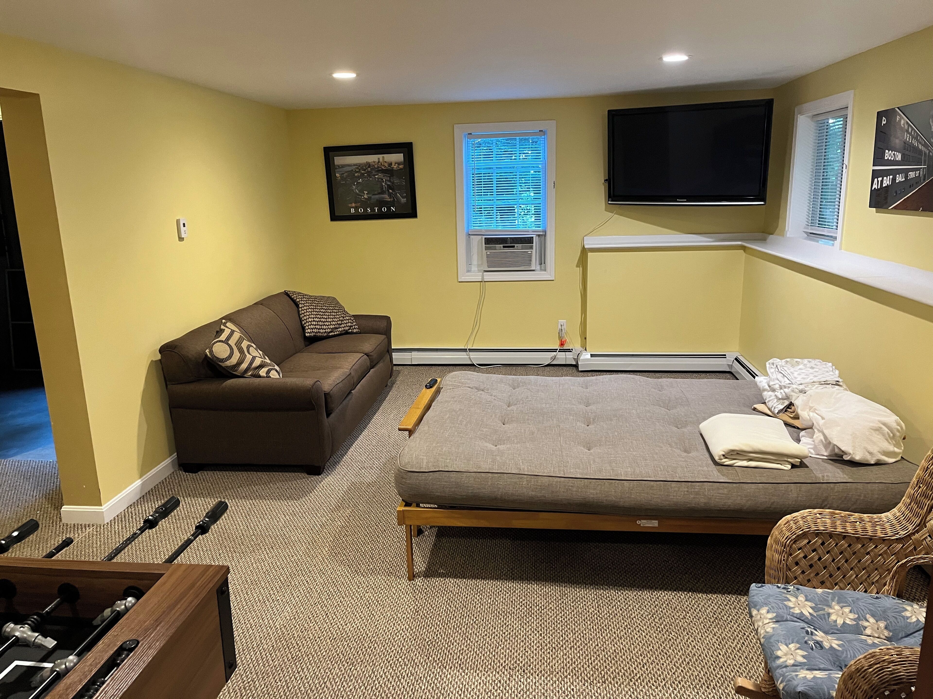 Una habitación con sofá, cama, televisión y ventana con persianas.