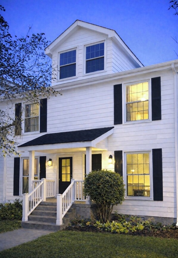 A two-story house with a front porch, a staircase, and a well-maintained lawn.