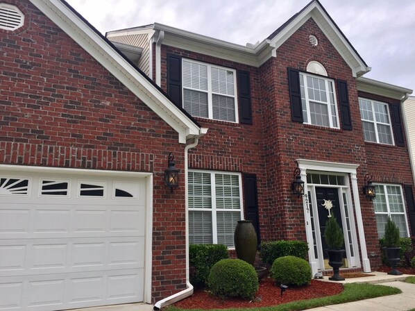 A two-story brick house with a white garage door, black shutters, and a front entrance with a doorbell. - Southern sophistication at Ashley Ridge (Summerville)