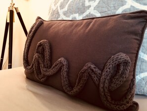 A brown pillow with a knitted design on a bed. - Southern sophistication at Ashley Ridge (Summerville)