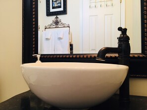 A white ceramic sink with a black faucet, a mirror with a decorative frame, and a towel rack with white towels. - Southern sophistication at Ashley Ridge (Summerville)