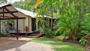 Ein Haus mit überdachter Veranda, umgeben von üppiger tropischer Vegetation.