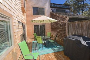 Un patio con mesa y sillas, una parrilla cubierta y una valla de madera.