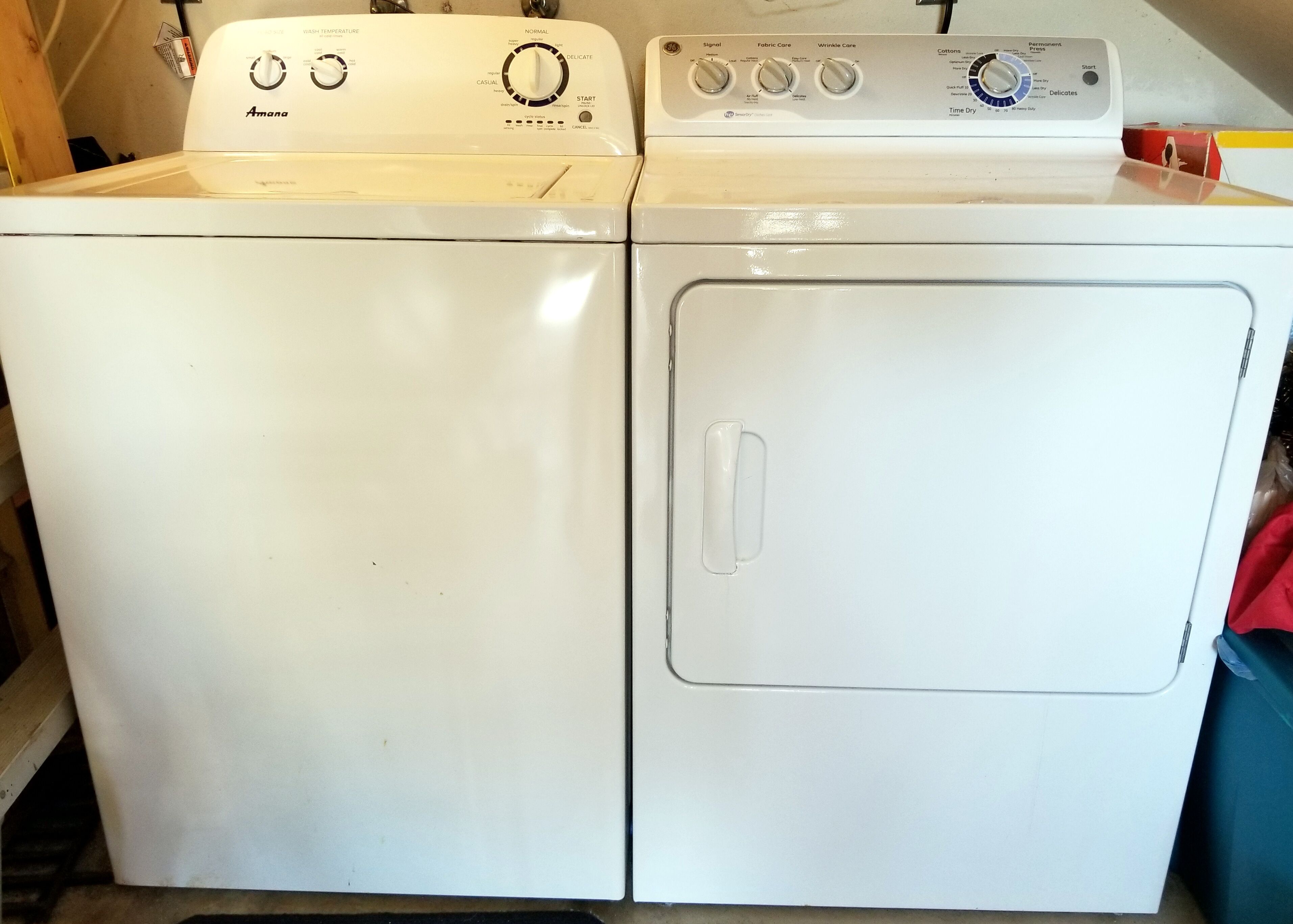 Vista frontal de una lavadora Amana blanca con puerta de carga frontal y panel de control con varias opciones.