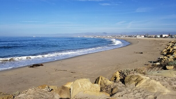 A beach with a rocky shoreline and a clear blue sky.
