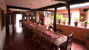 A spacious dining area with a long wooden table, multiple chairs, and potted plants. - Casa Alexandra. Puerto Vallarta Traditional Comfort. (Puerto Vallarta)