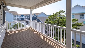 A covered wooden deck with white railings, overlooking a residential area with multiple houses. - 12th St / bayside - 4 br multi level townhouse. Nicely furnished and well cared for. (Ocean City)