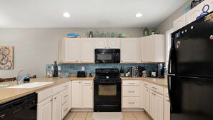 A modern kitchen with white cabinets, a black stove, a black refrigerator, and a microwave. - 12th St / bayside - 4 br multi level townhouse. Nicely furnished and well cared for. (Ocean City)