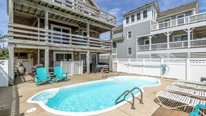 A backyard with a swimming pool, outdoor seating, and a partially constructed building. - Blue Heron | 955 ft from the Beach | Private Pool, Hot Tub | Nags Head (Nags Head)