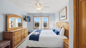 A bedroom with a bed, wooden dresser, and a ceiling fan. - Blue Heron | 955 ft from the Beach | Private Pool, Hot Tub | Nags Head (Nags Head)