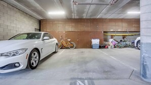 A parking garage with a white car and a bicycle.