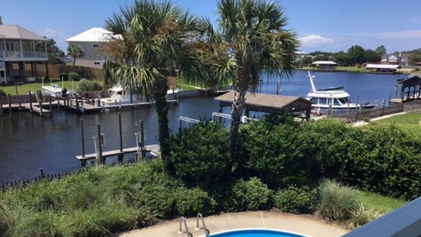 A swimming pool with a dock and boats in the background. - Perdido Key/Pensacola Pass sleeps 14 (Pensacola)
