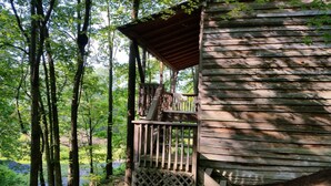 Une cabane en bois dotée d’une terrasse en bois et d’un petit porche.