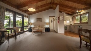 Ein geräumiges Wohnzimmer mit hoher Decke und großen Fenstern, einer gemütlichen Sitzecke und einer modernen Küche.