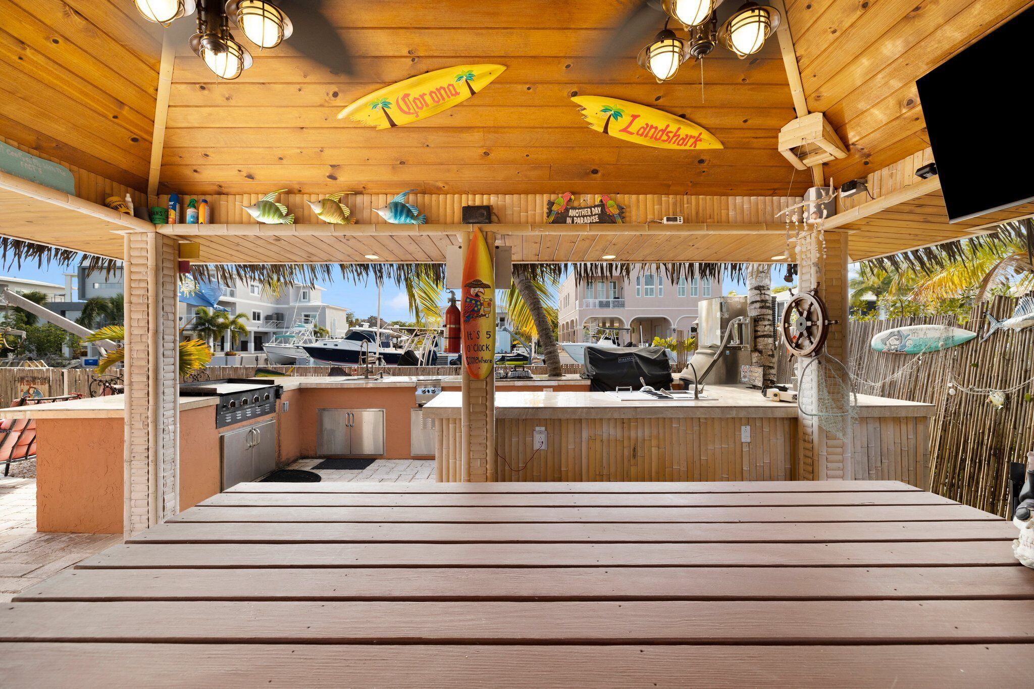 Un espace bar extérieur doté d’un plafond en bois, de tabourets de bar et d’un barbecue.