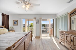 Una camera da letto con un letto, una cassettiera, un ventilatore a soffitto e un balcone con vista all'esterno.