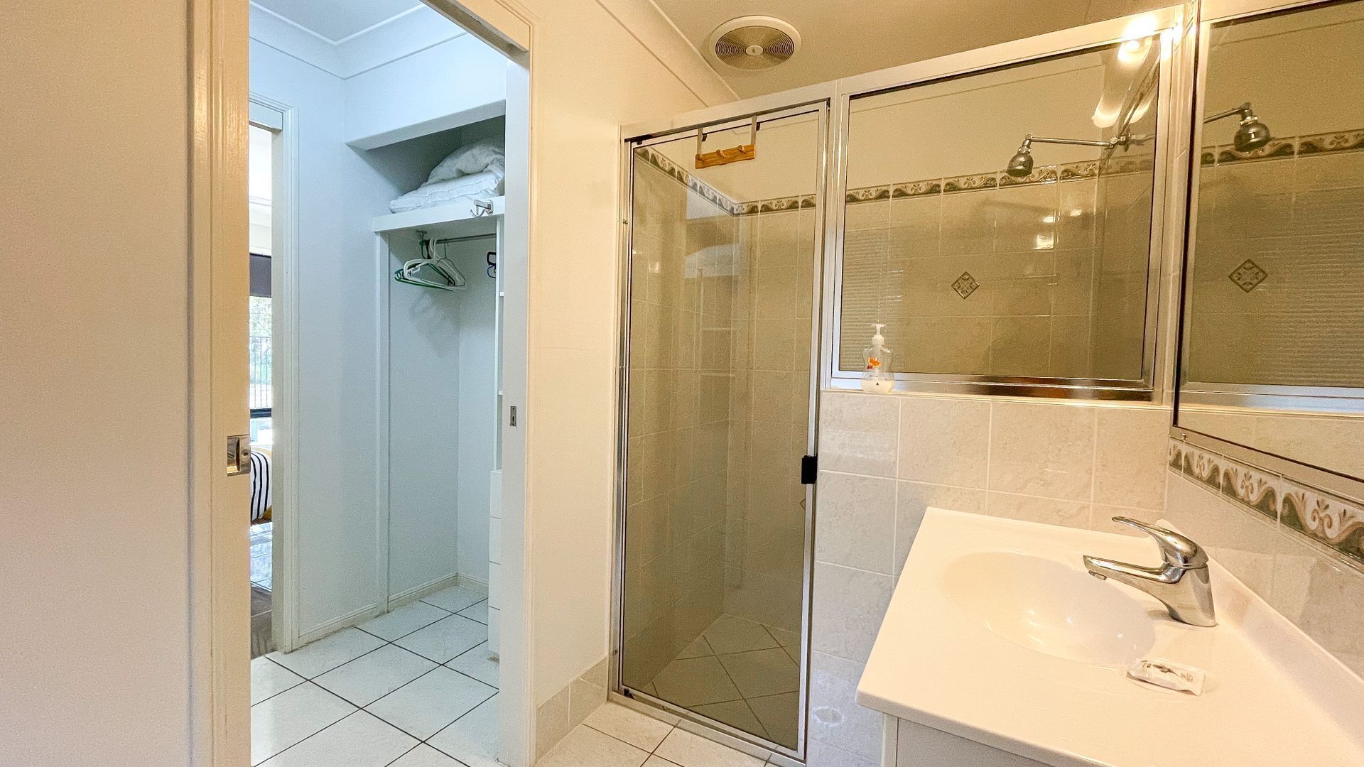 Un bagno moderno con cabina doccia in vetro, lavabo bianco e specchio con pannello decorativo.