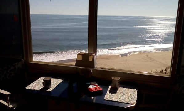 A view of the ocean through a window, with a table in the foreground.