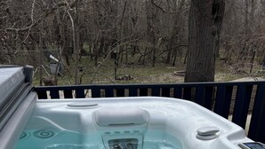 Een hottub met bedieningspaneel, afvoer en uitzicht op een bebost gebied.
