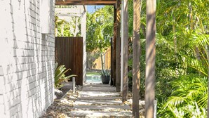 A pathway leading to a pool with a wooden pergola and lush greenery. - Elanda St - Luxurious Beachside Living (SUNSHINE BEACH)