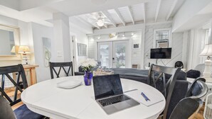 Ein moderner Essbereich mit einem runden Tisch, Stühlen, einem Laptop und einer Blumenvase.