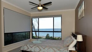 A bedroom with a large window, a bed, a ceiling fan, and a nightstand. - Wahroonga On The Water (Kingscote)