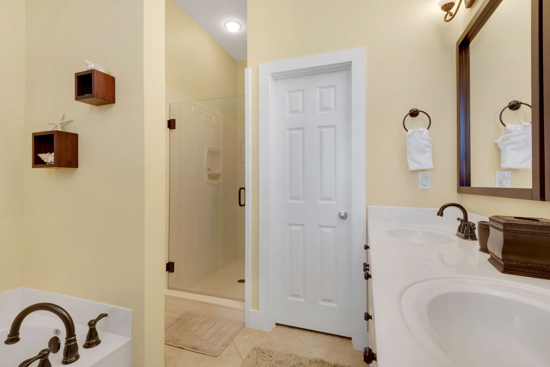 Une salle de bain avec un lavabo blanc, une cabine de douche en verre et une porte blanche.