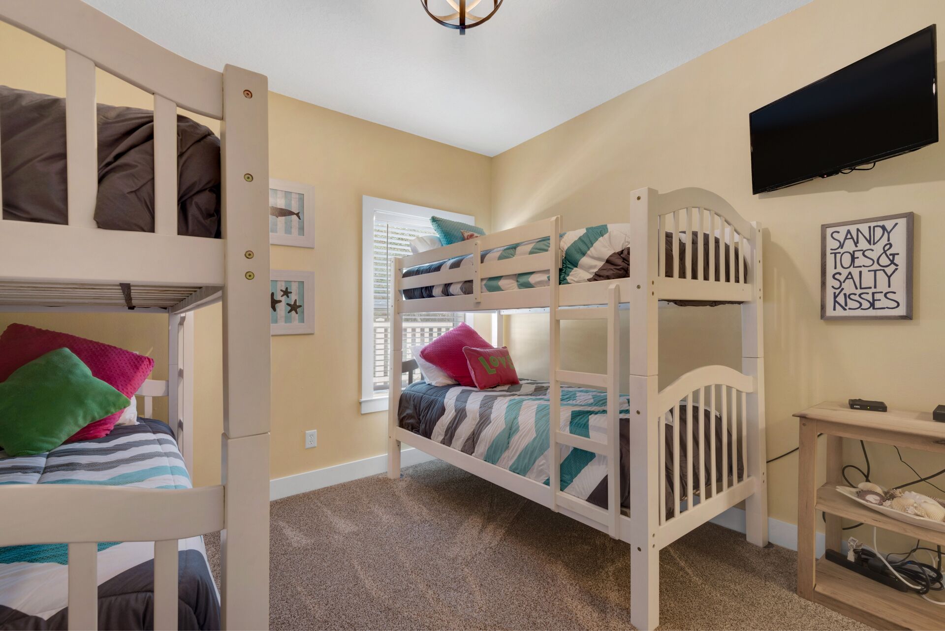 A bunk bed room with a television and a framed quote on the wall.