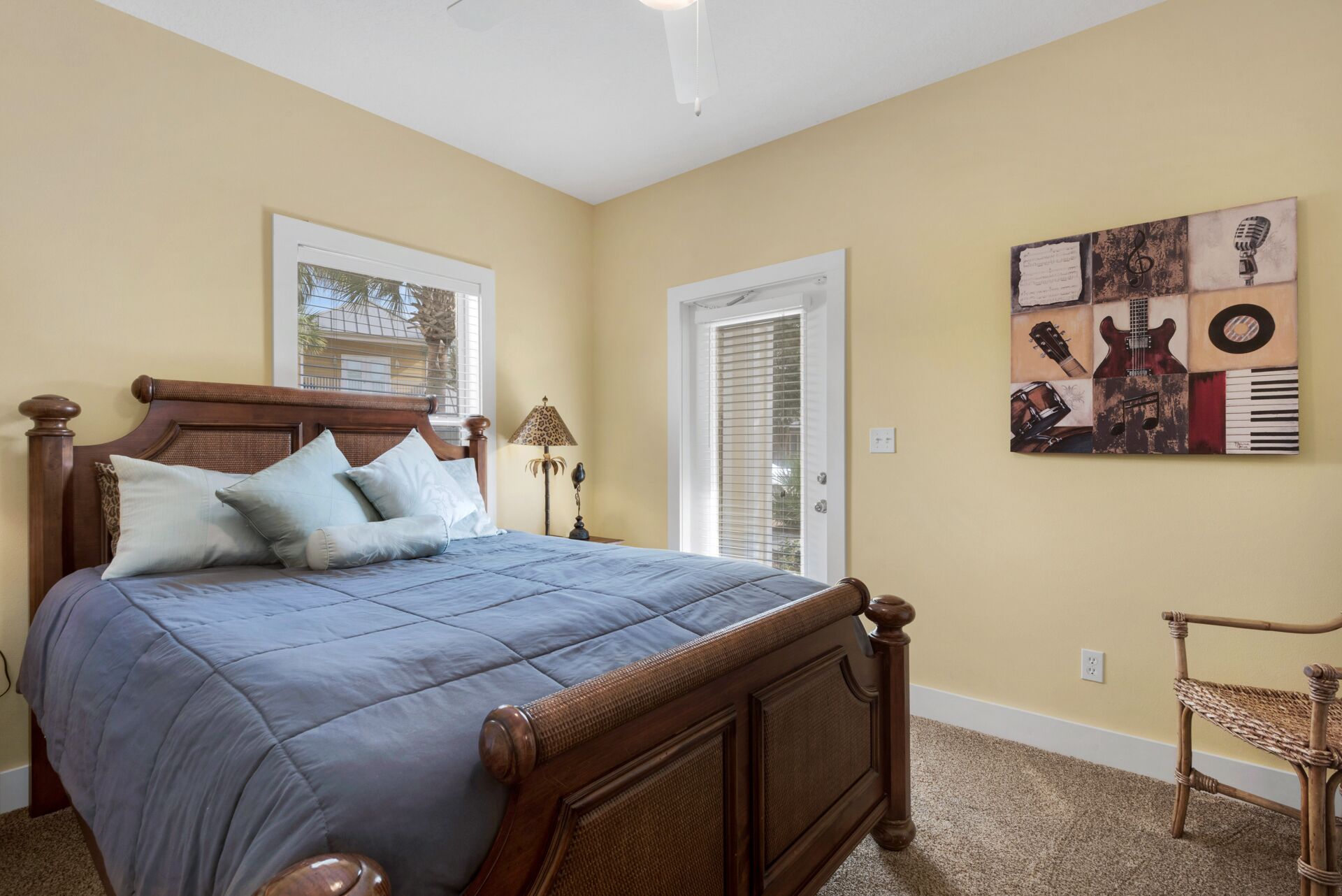 A bedroom with a wooden bed, a window, a door, and a wall art piece.